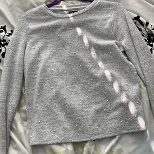 a grey long sleeve shirt with pearls